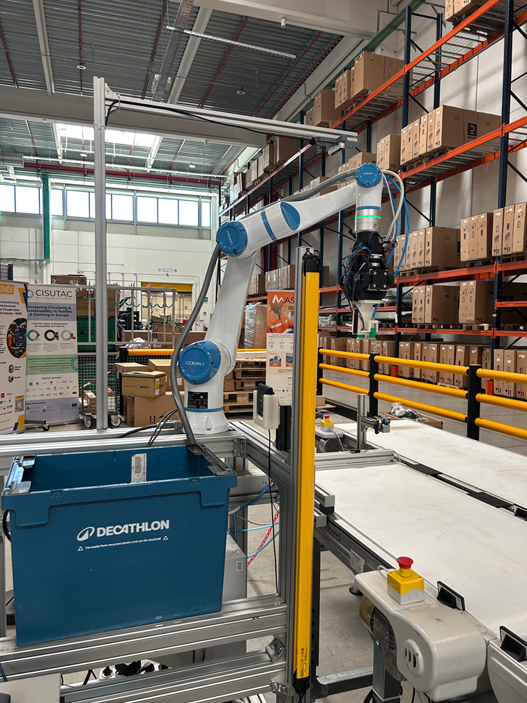 Braço colaborativo MyCo diante de uma caixa azul da Decathlon e estantes com caixas.