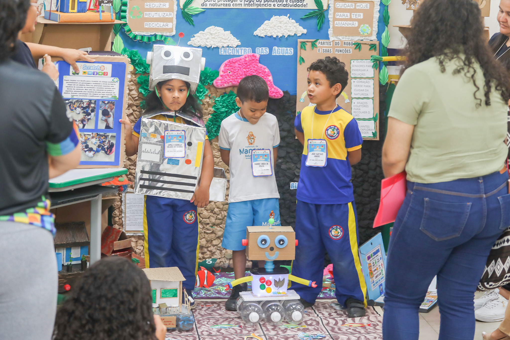 Estudantes apresentam um projeto de robótica e preservação ambiental diante de visitantes.